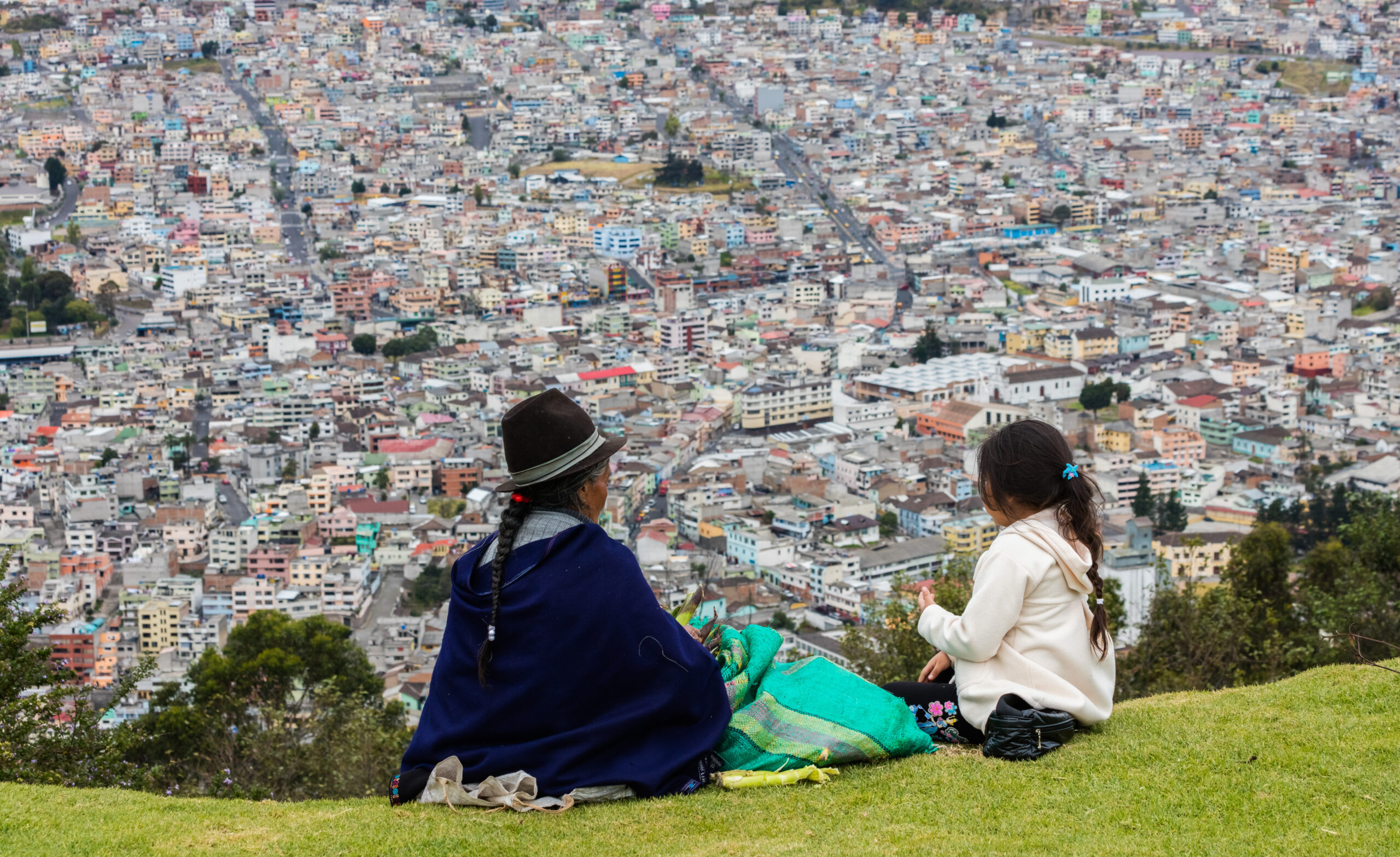 Indigenous people peeling maize while overlooking Quito from El Panecillo, Ecuador